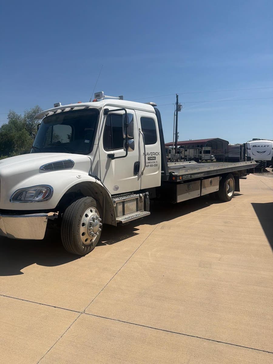 Maverick Towing white flatbed tow truck with an empty bed, seen from the front