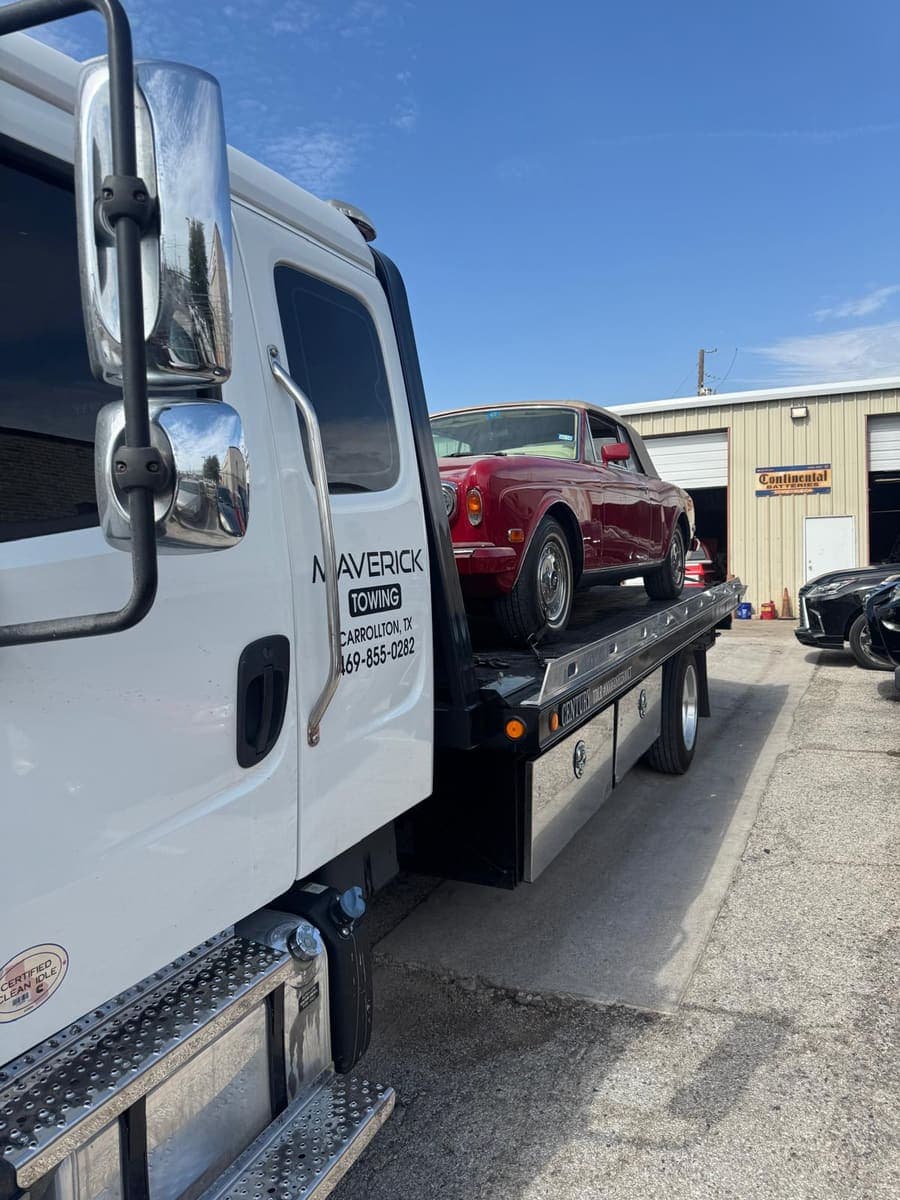Red Rolls-Royce Corniche convertible loaded on a Maverick Towing flatbed outside a repair shop