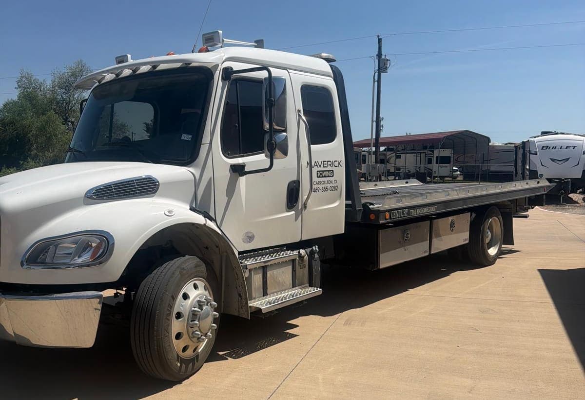 Maverick Towing white flatbed tow truck parked under a clear Texas sky, ready for dispatch